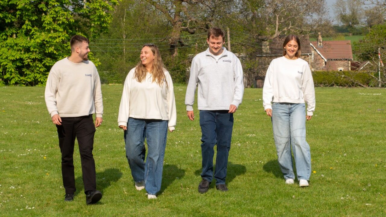 Compelite Pro team walking together through a green field in branded sweaters