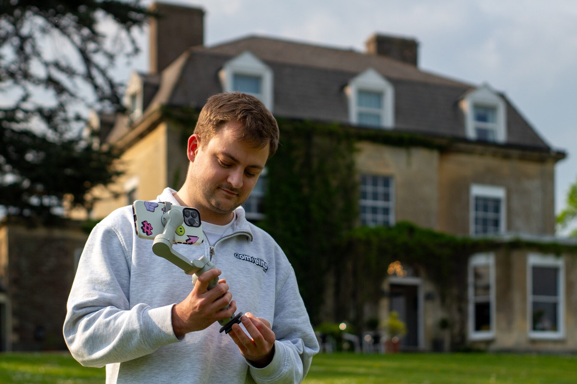 Compelite Pro content creator filming on location with a gimbal-mounted iPhone outside a Cotswolds country house