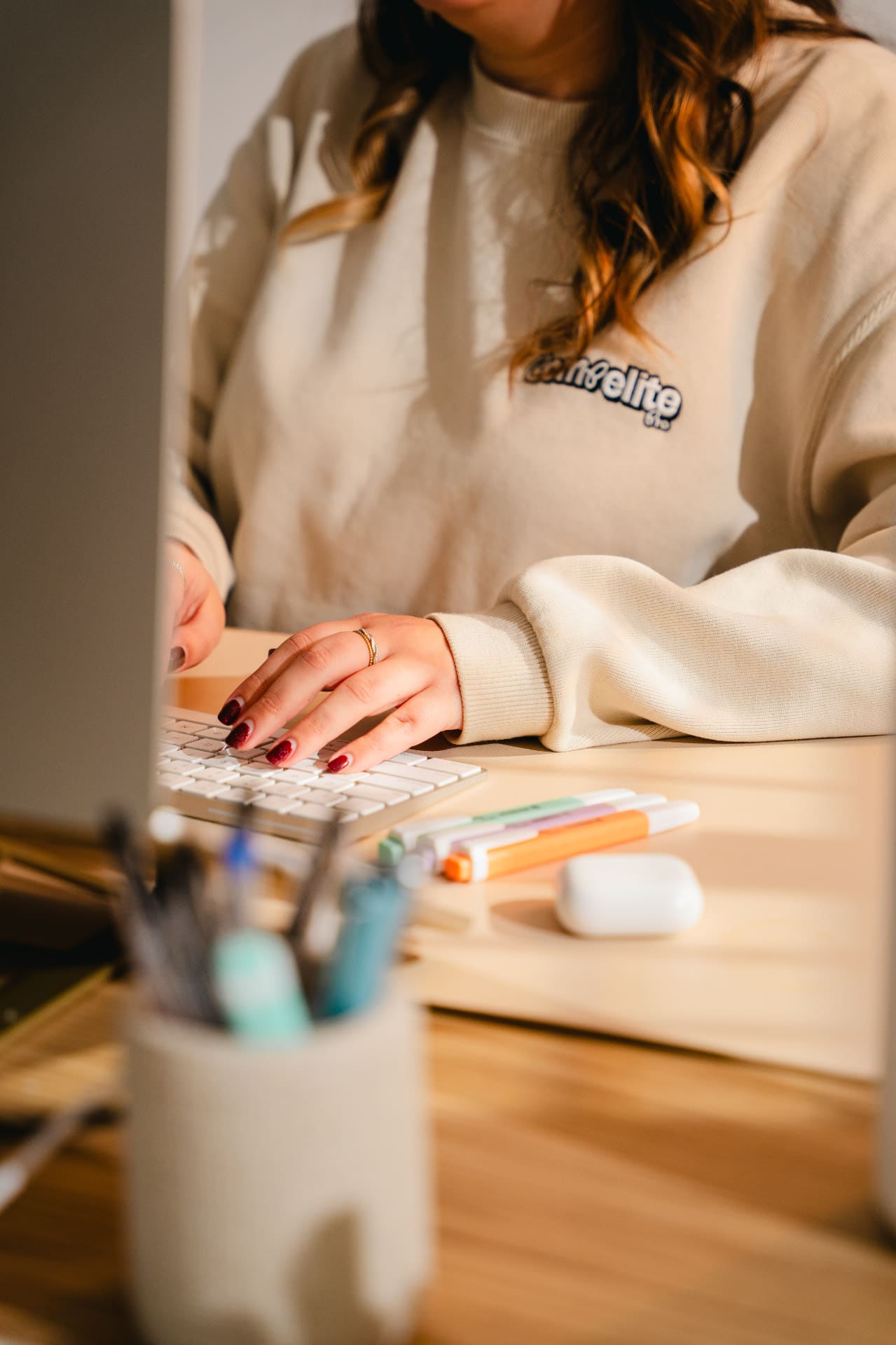 Compelite Pro team member typing at a desk in a branded sweatshirt