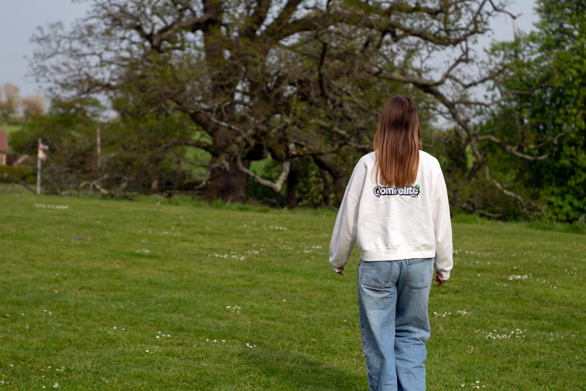 Compelite Pro team member walking through a green field in branded sweater