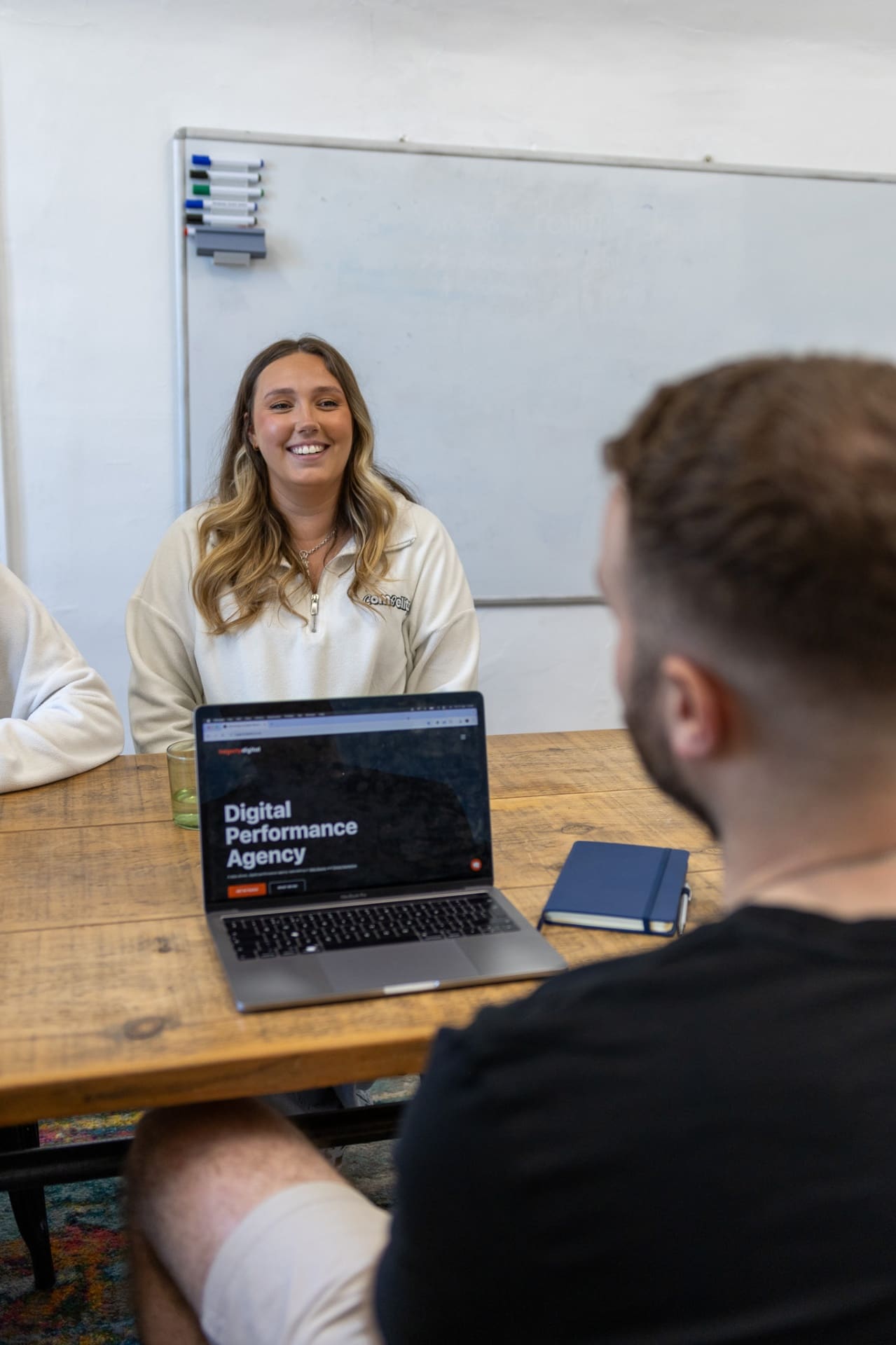 Compelite Pro team meeting with a partner agency around a laptop showing a Digital Performance Agency website — collaborating with our trusted SEO, PPC and web design partners