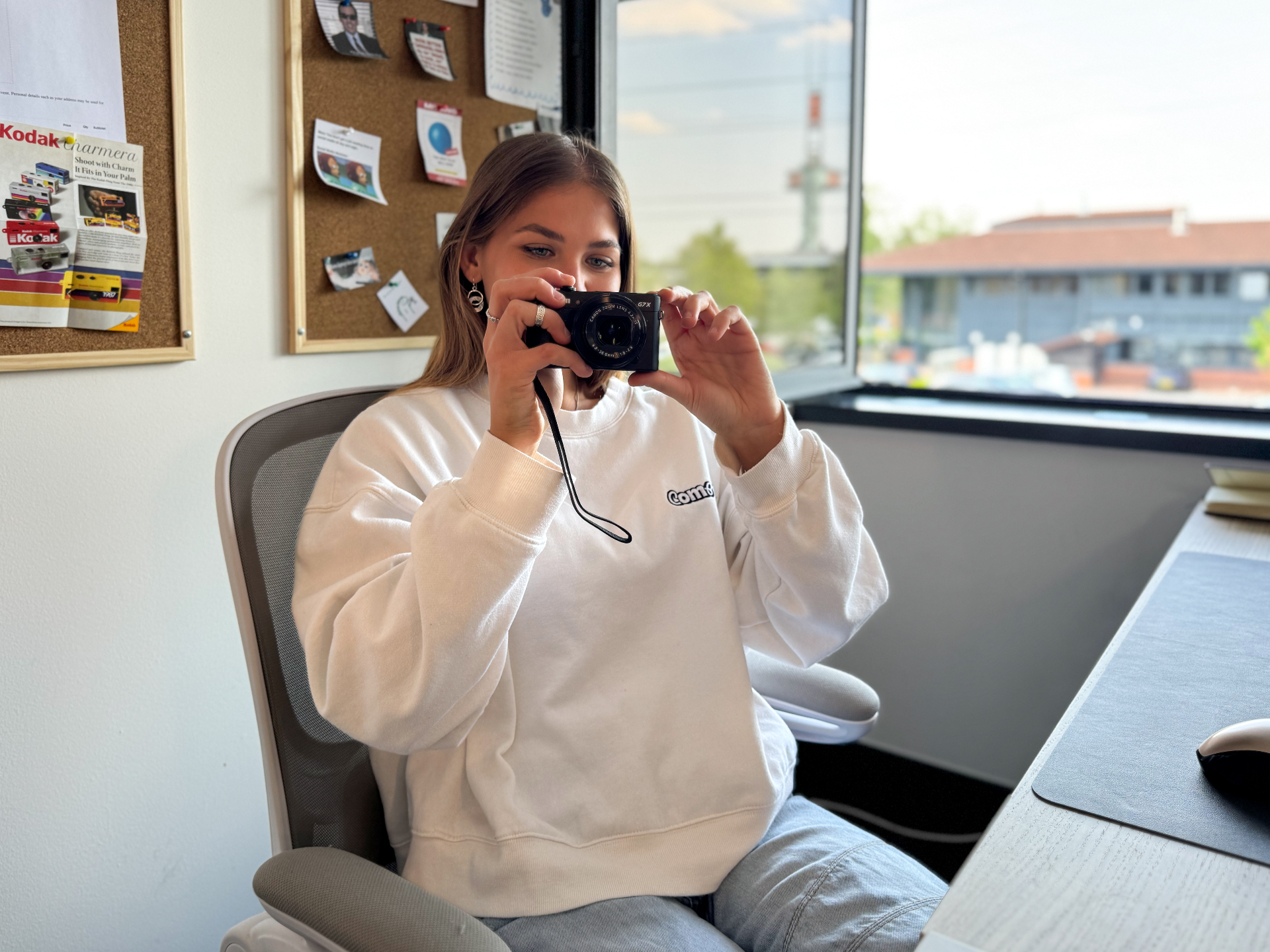 Compelite Pro team member in branded sweatshirt capturing content with a Canon G7X camera in the studio