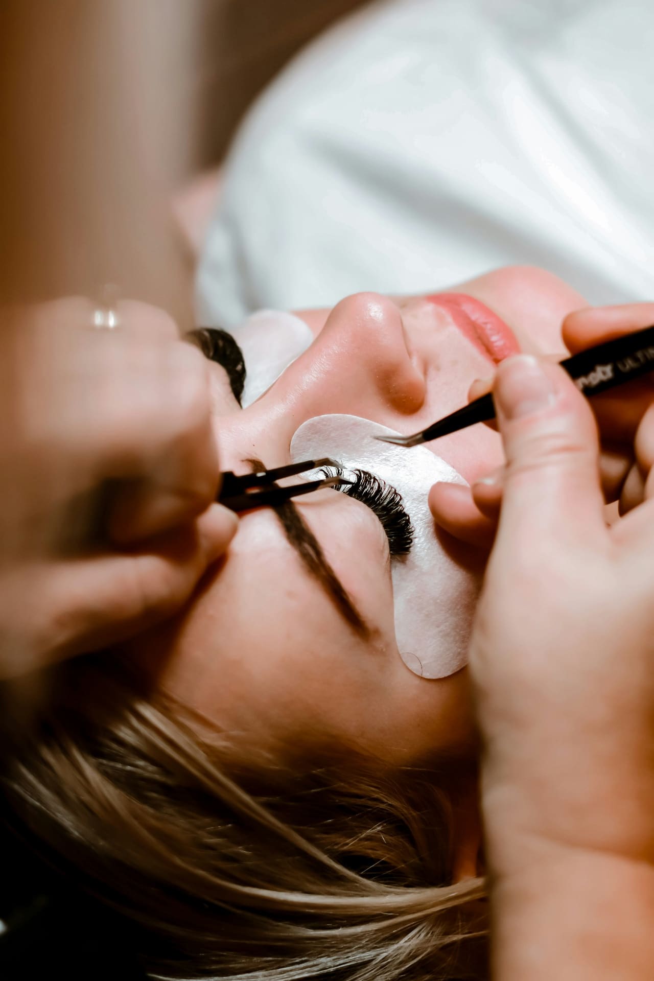Lash technician carefully applying eyelash extensions to a client in a beauty salon — social media agency for beauty brands and salons