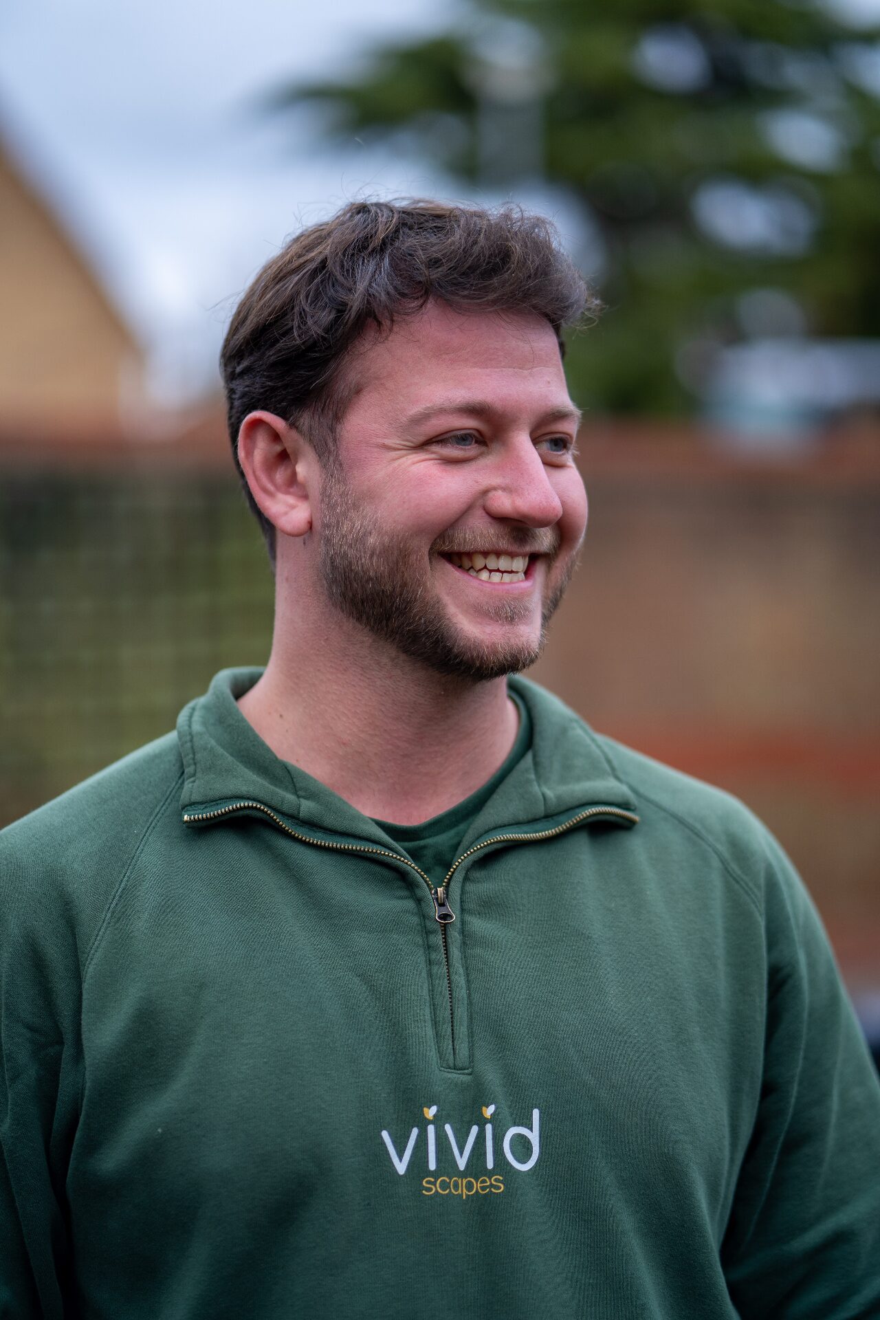 Vivid Scapes team member smiling in branded green sweatshirt