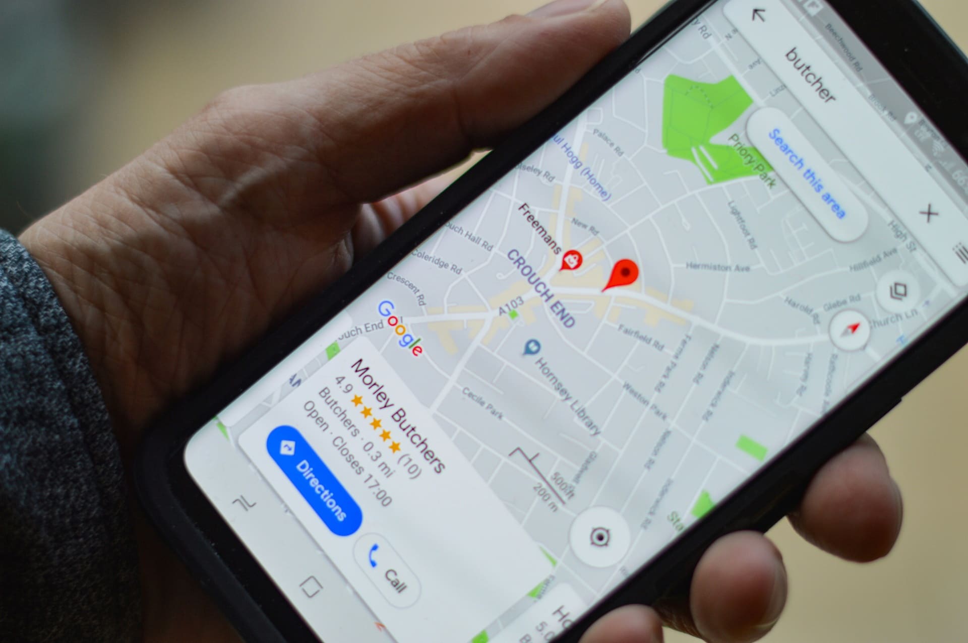 Person holding a phone showing a local business on Google Maps with reviews and Directions button — Google Business Profile in action