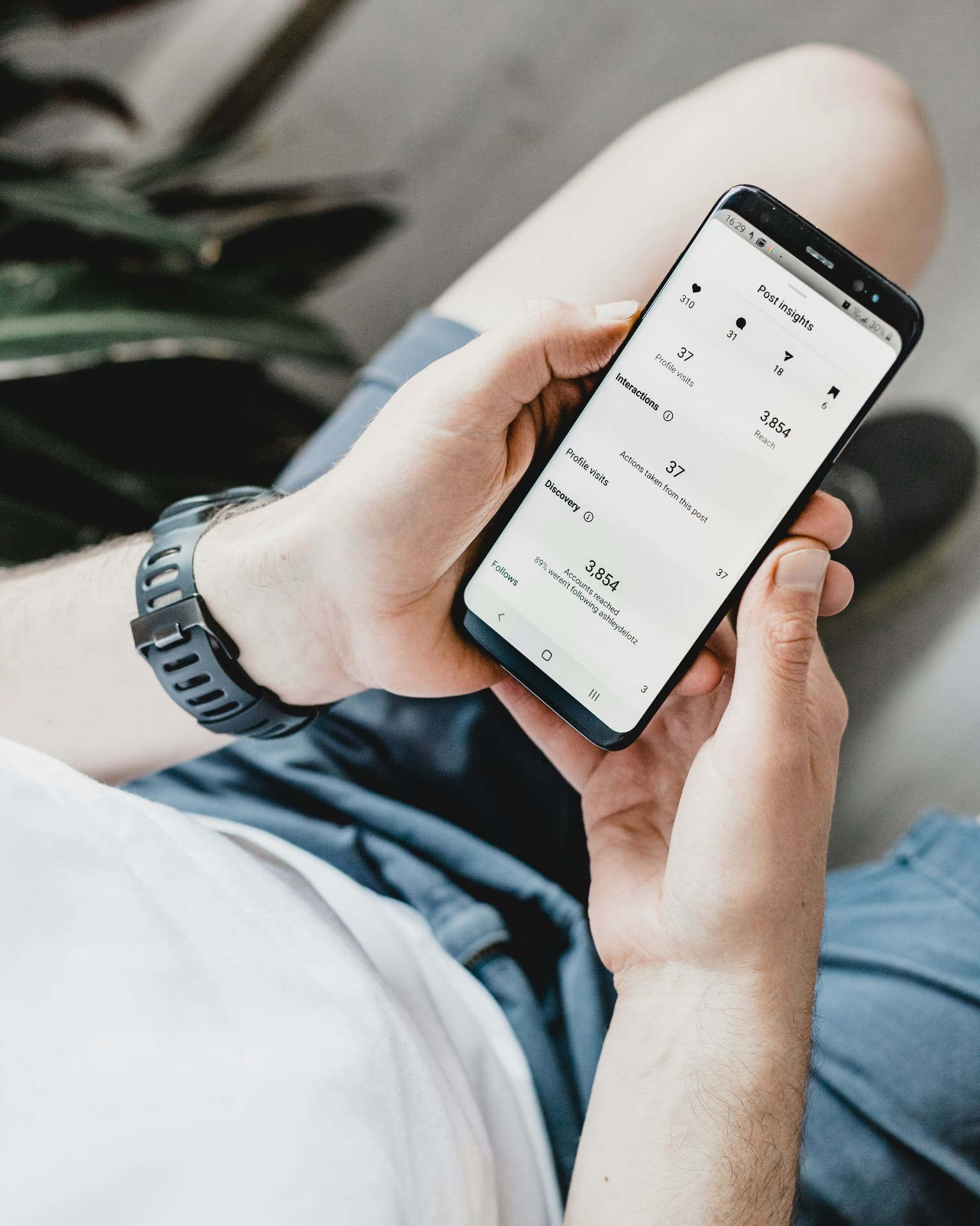 Person checking Instagram post insights on a phone showing reach, profile visits and engagement metrics — Instagram engagement and DM management