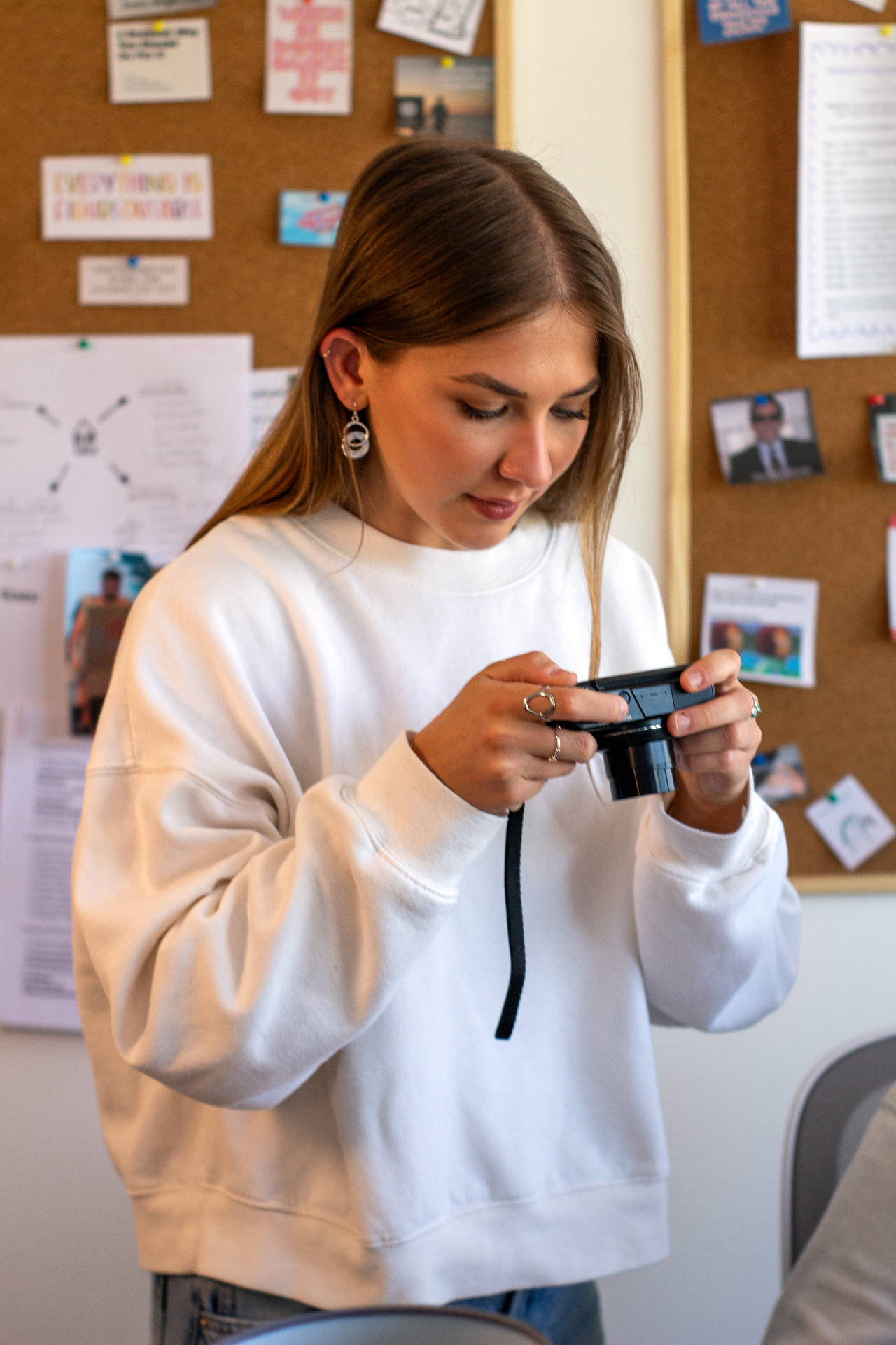 Compelite Pro social media manager reviewing footage on a compact camera in front of the studio moodboard